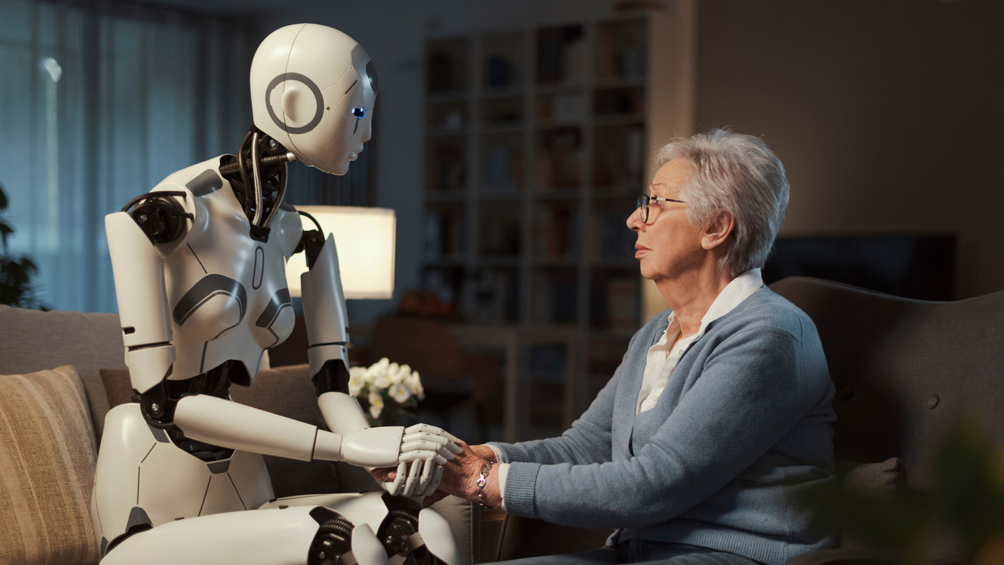 Ein sitzender Roboter hält die Hand einer älteren Dame