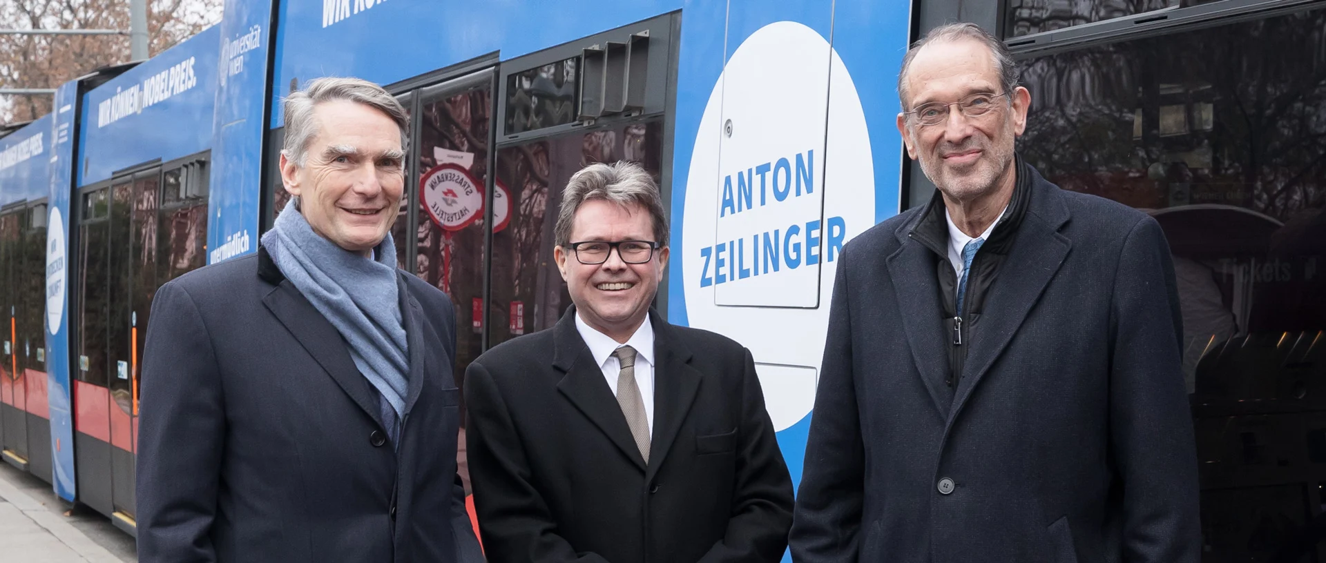 Sebastian Schütze, Martin Polaschek und Heinz Faßmann stehen vor einer zu Ehren Anton Zeilings gefärbten und eigens bedruckten Straßenbahn