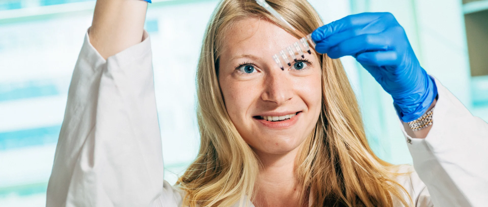 Eine Forscherin in einem Labor hält eine Pipette hoch.