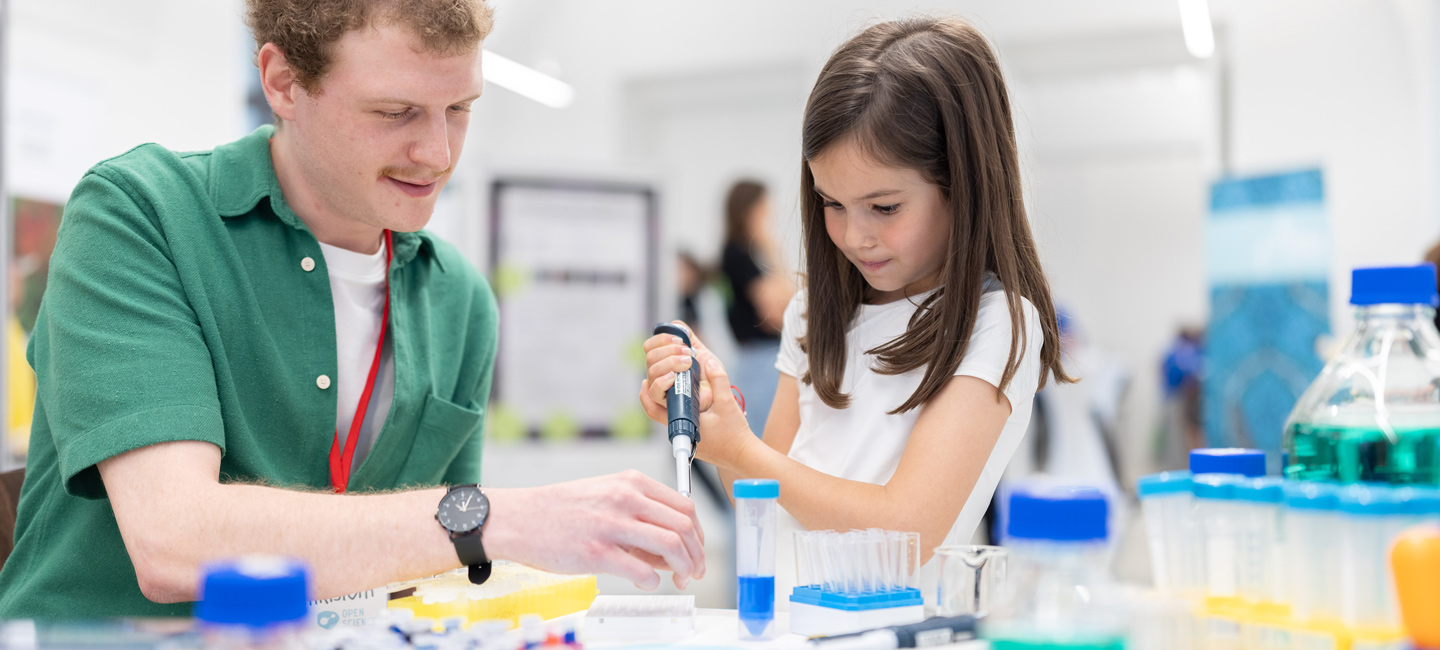 Ein Forscher und ein Mädchen bei einer Experimentierstation der Langen Nacht der Forschung