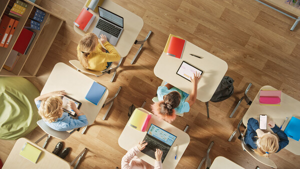 Aufnahme eines Klassenzimmers von oben mit vor Laptops sitzenden Kindern
