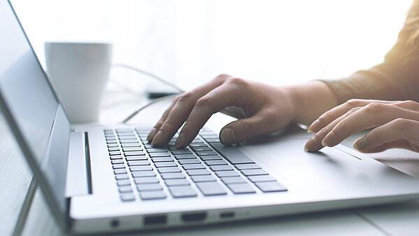 Eine Hand liegt auf einer Laptop-Tastatur